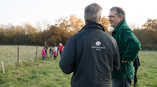 Man in Woodland Trust jacket giving advice to another man