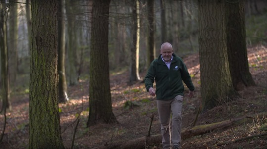 Site manager Mark Feather walking through woods