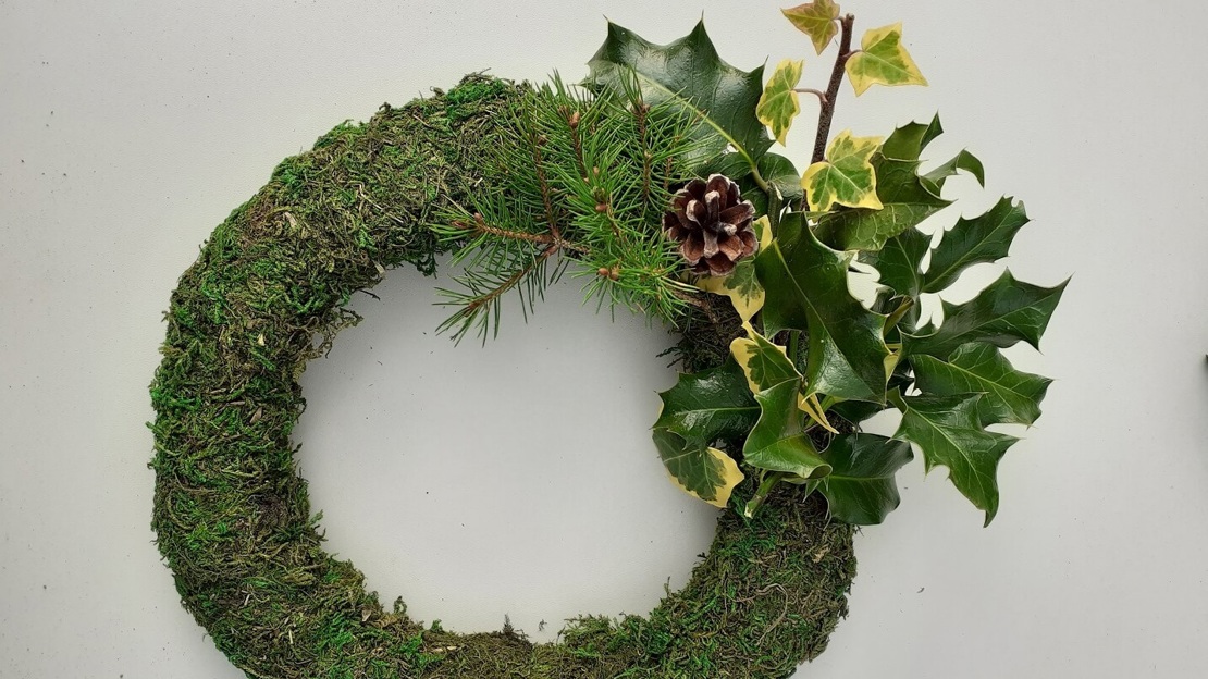 Close up of wreath base with one quarter covered in foliage