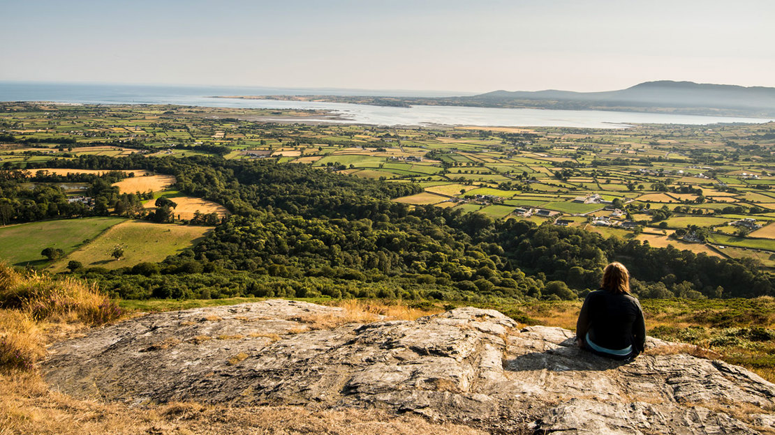 Person sitting on a rock enjoying the view at Mourne Park