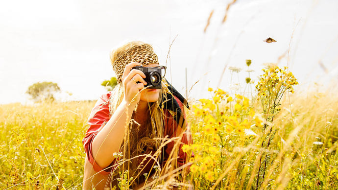young woman photographing with camera in field