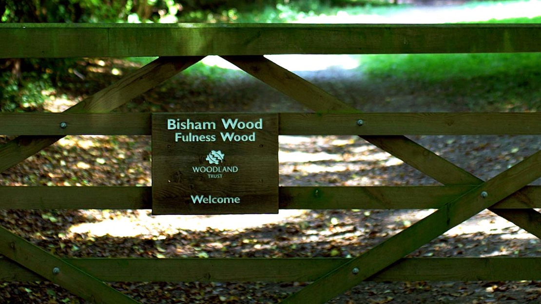 Woodland Trust Bisham Woods sign on five-bar gate