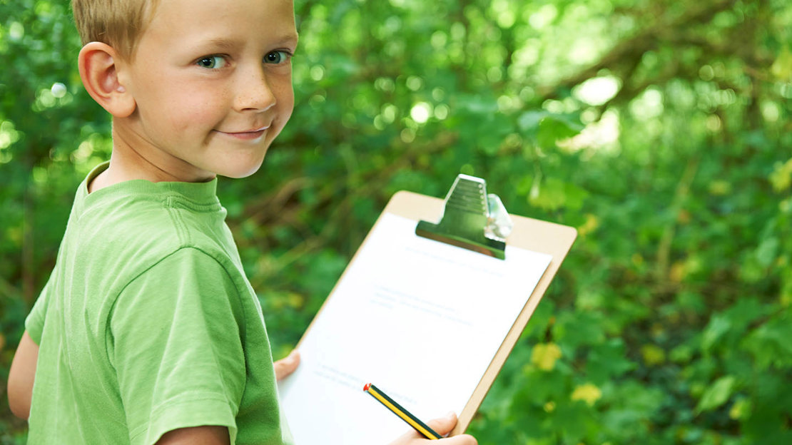 Boy filling in a survey on a clipboard