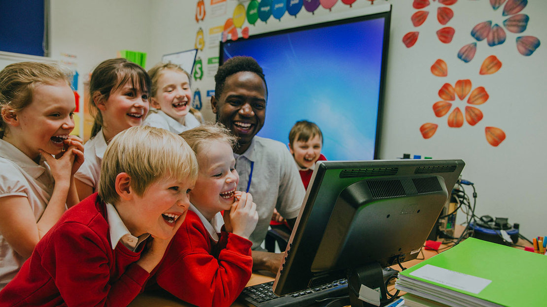 Happy pupils working together on a computer
