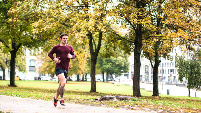 Man running beside city trees