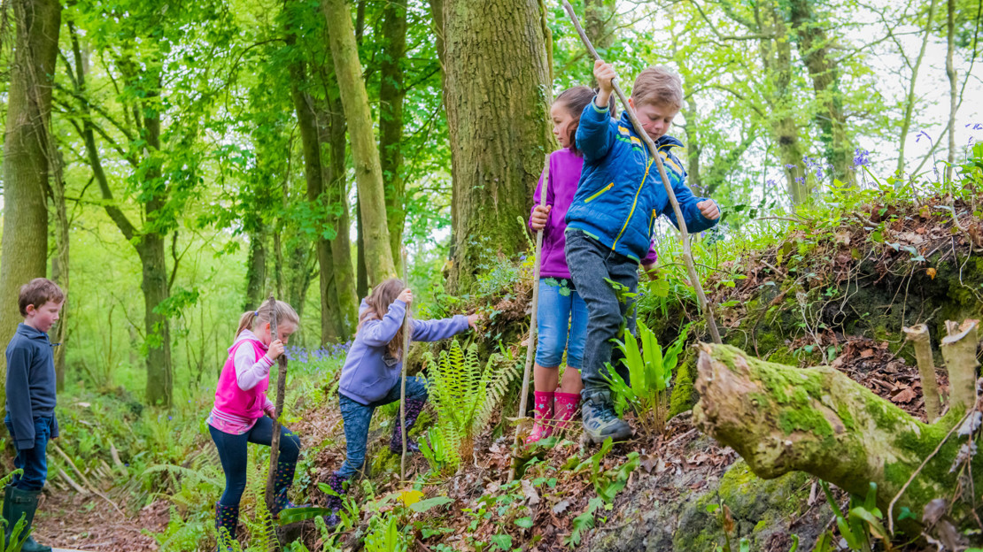 Children on scavenger hunt climbing with sticks