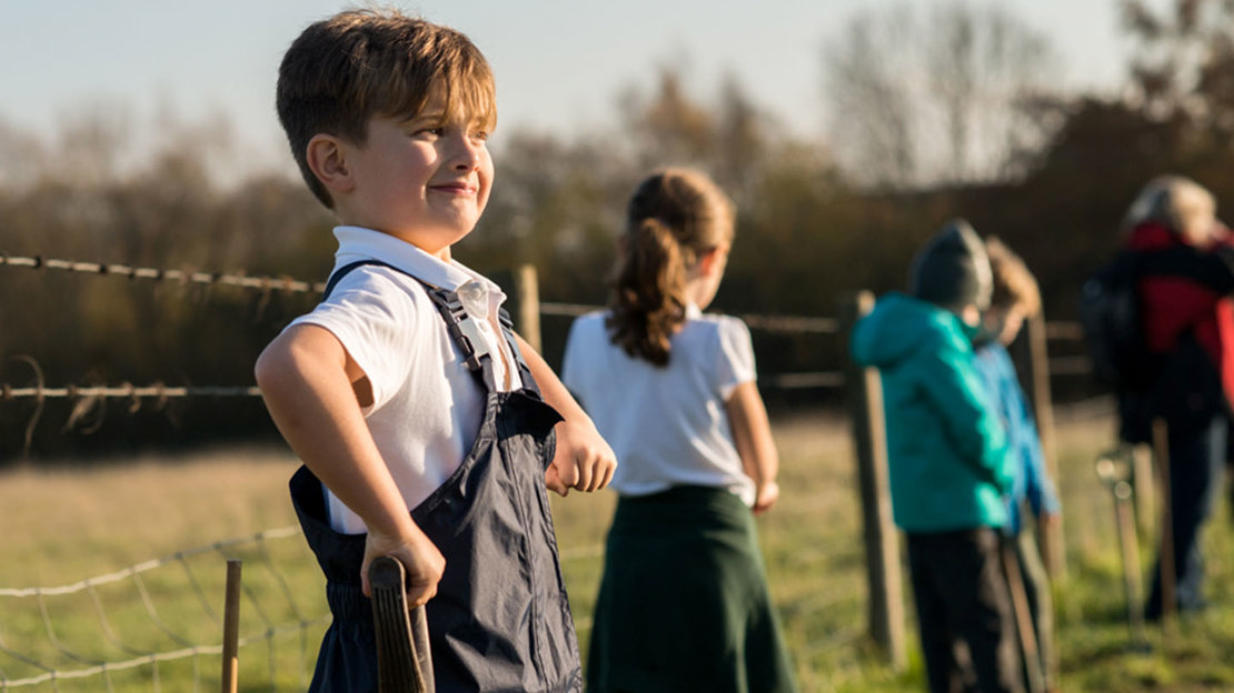 Boy smiling proudly, onlooking planting event at Mead.