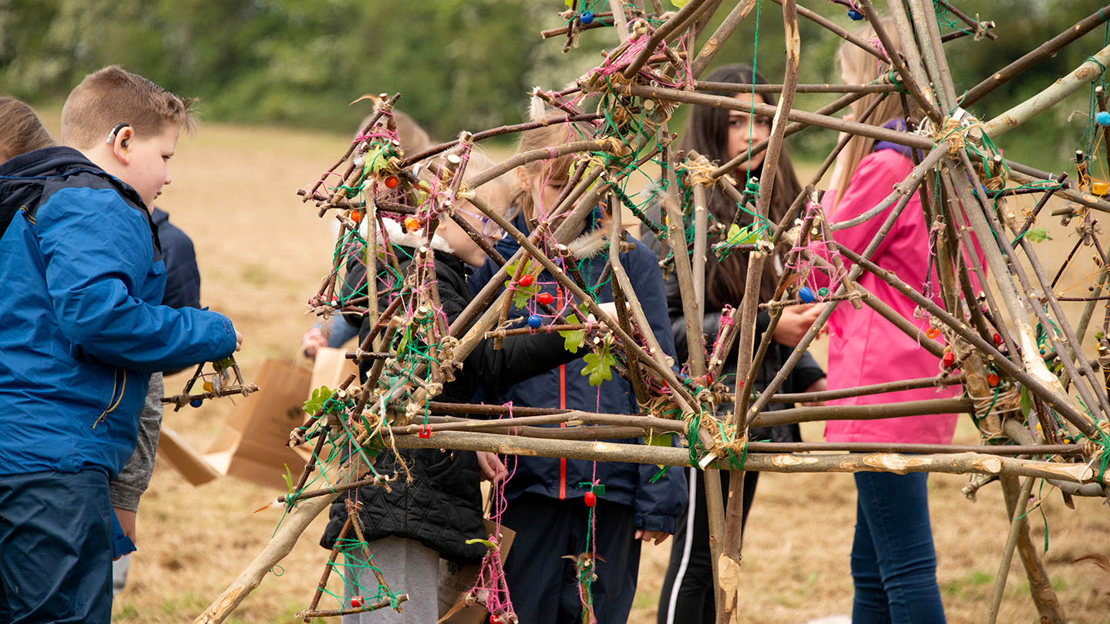 School children creating a art structure from twigs at Mead.