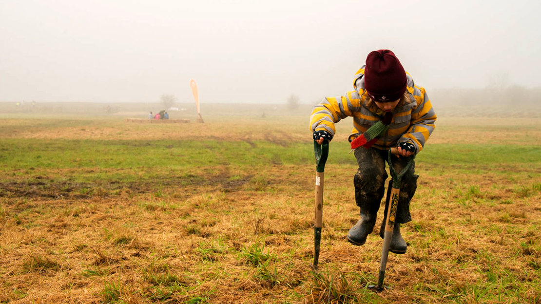 School boy playing with spades. Using them like pogo sticks.