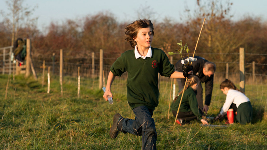 Schoolboy running with sapling and cane in hand.