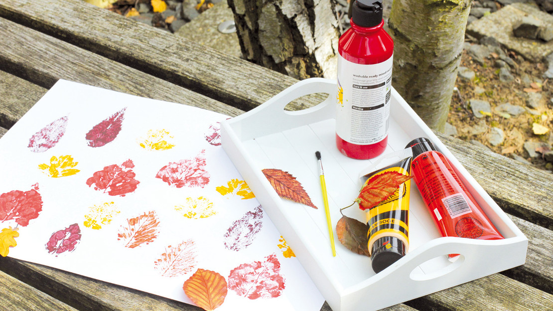 Leaf printing on paper with paint and supplies on a tray