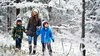 Three children exploring a snowy woodland