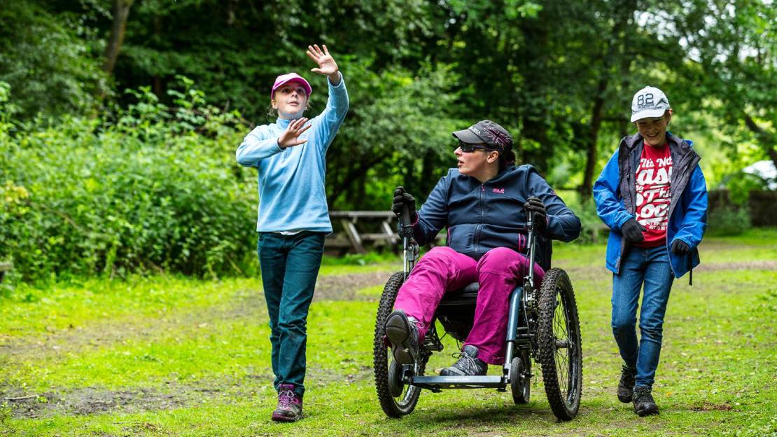 Children and wheelchair user exploring woodland