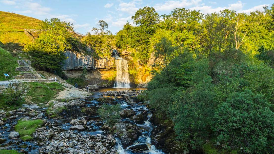 Waterfall cascading over a ledge surrounded by woodland