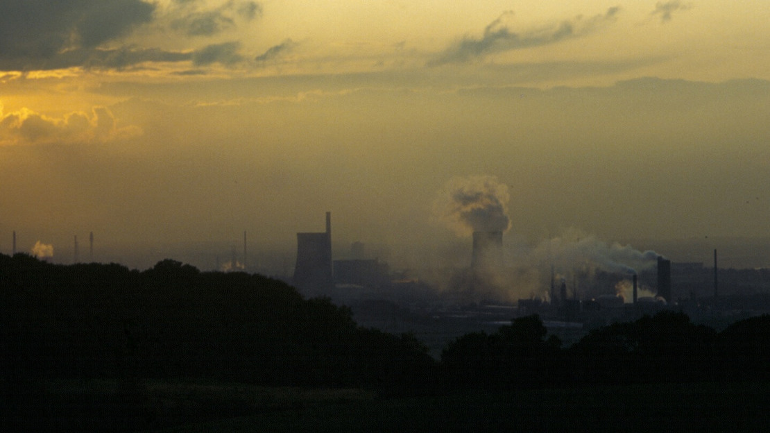 Town in the distance at sunset with chimeys and smoke visible on the horizon