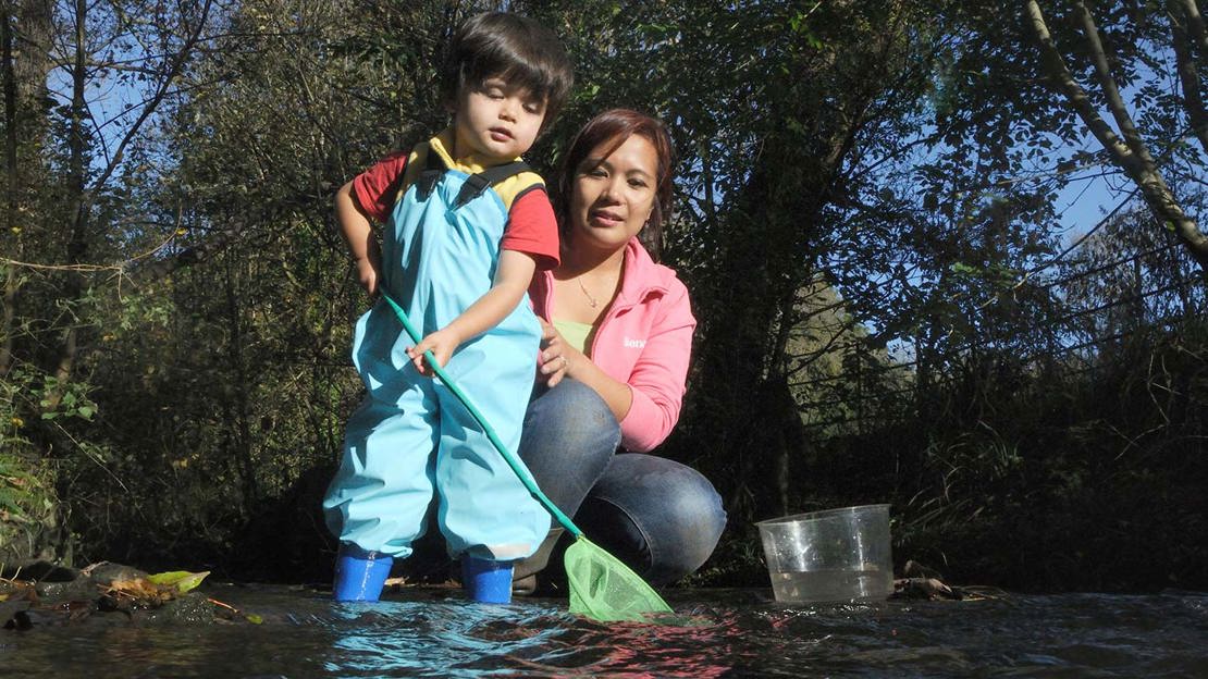 Mother holding son while he pond dips