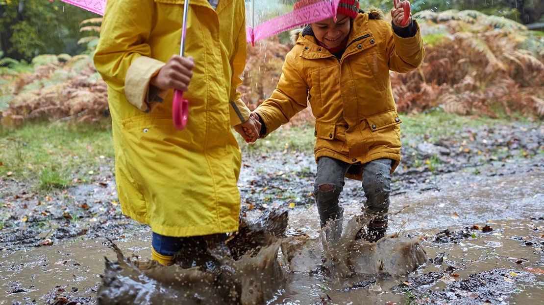 Parent and child splashing in muddy puddle