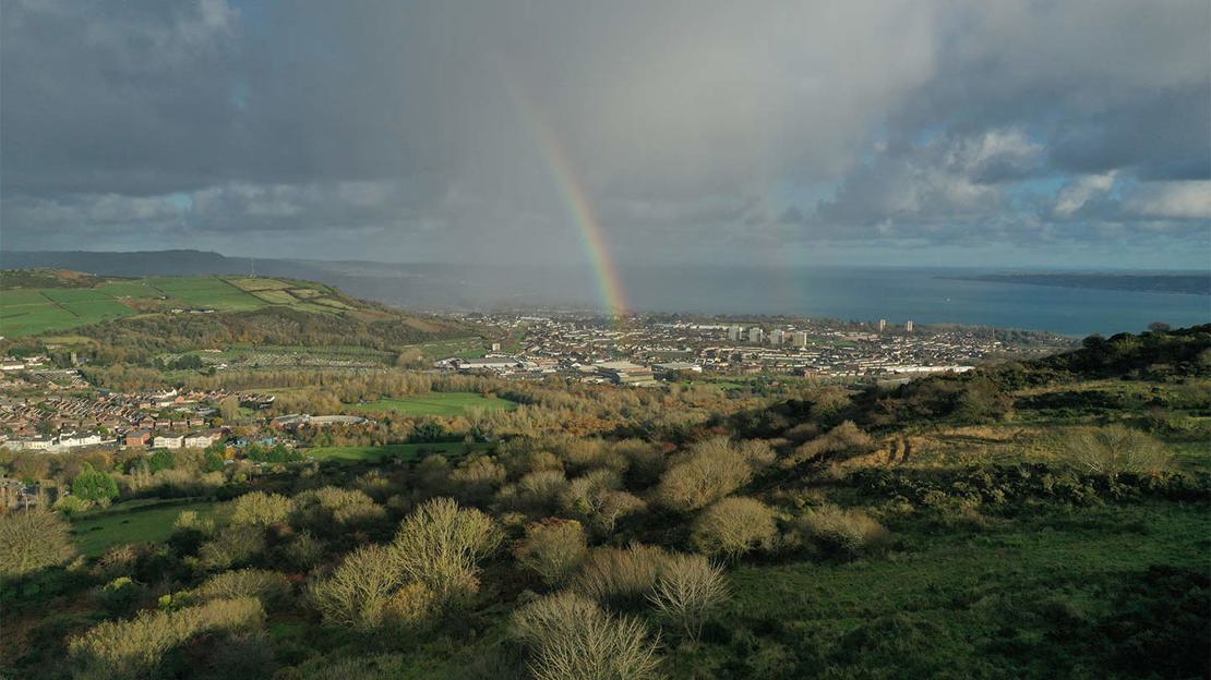 Rainbow on a rainy day on the hills above a city