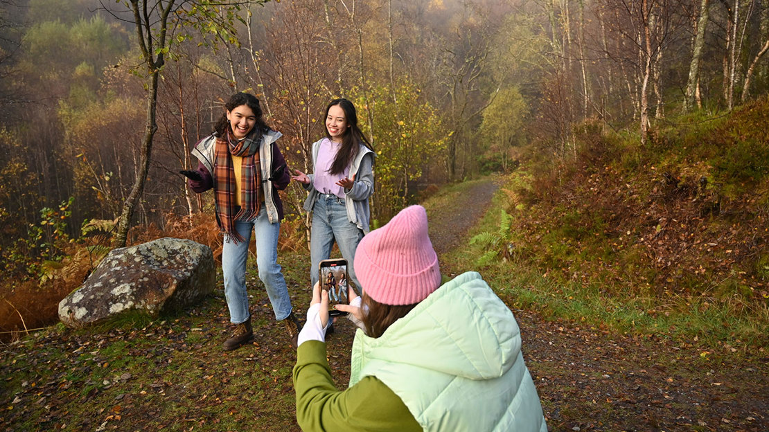 teen girls record video in autumn woods