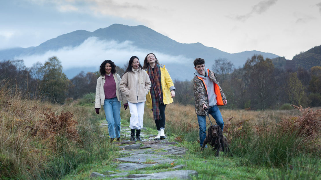 four young people walking a dog at Glen Finglas