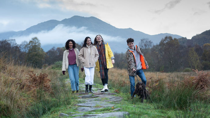 four young people walking a dog at Glen Finglas