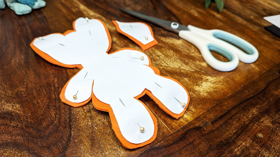 A fox shape cut out of a piece of orange felt using a pinned-on template