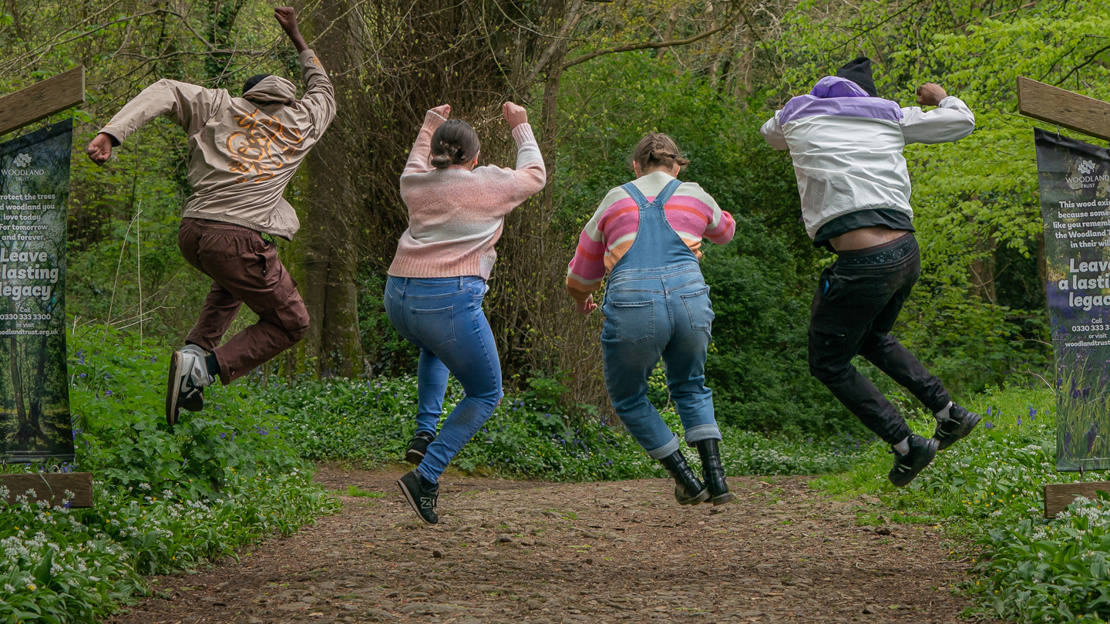 People jumping on a woodland path People jumping on a woodland path