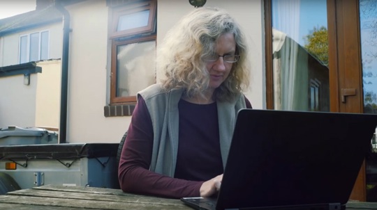 Volunteer Suzie Harvey working on a laptop in her garden