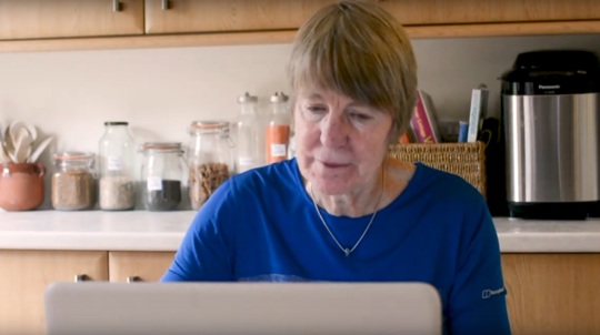 Volunteer Alison Stewart on a laptop in her kitchen