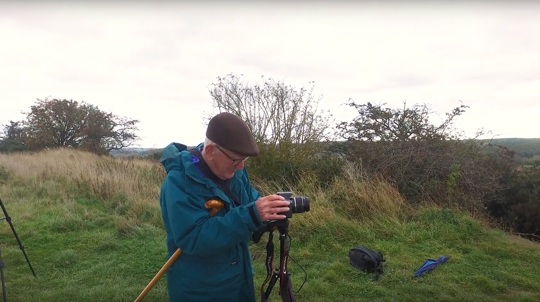 Volunteer David Rodway setting up a camera and tripod in a wood