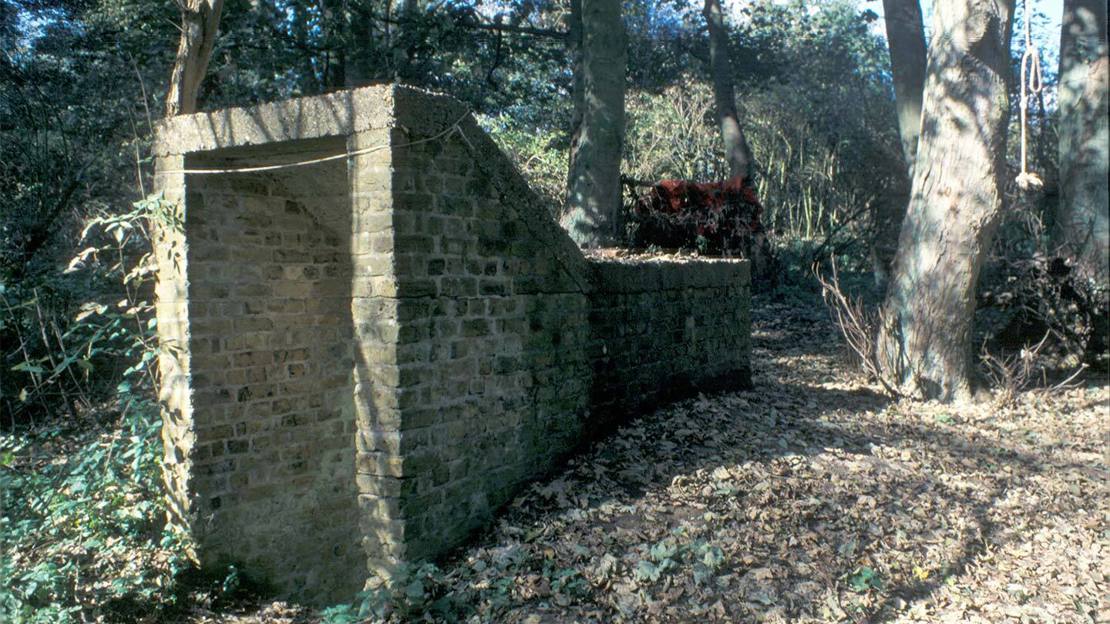 A brick structure marking a tunnel entrance in woodland