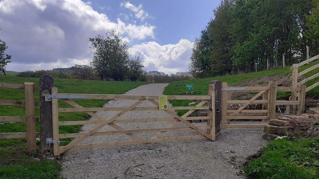 Wooden gate with path leading to trees in background.