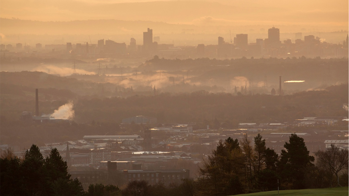 Hilltop view towards distant city buildings in the mist.