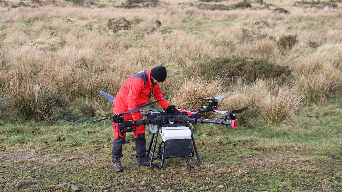 Large drone on the ground being examined by a person.