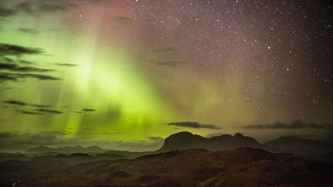 Northern Lights in the night sky above mountain.