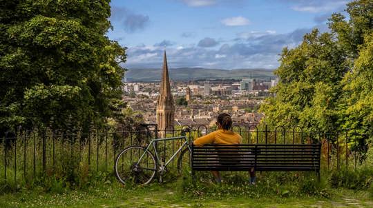 Person sitting on park bench overlooking city.