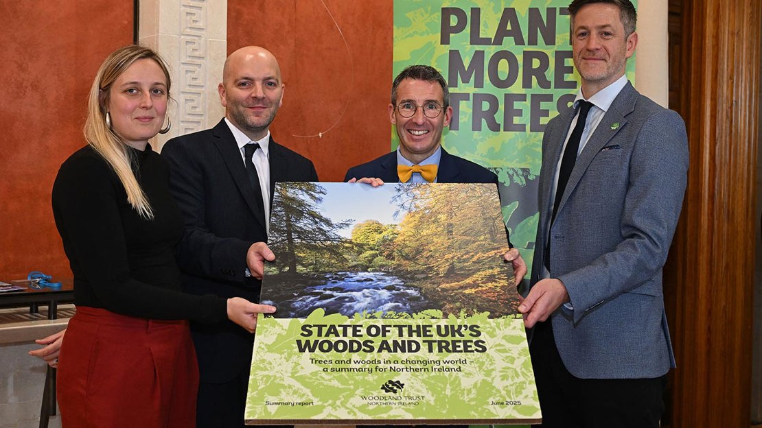 Woodland Trust staff and DAERA Minister holding cover image for State of Woods and Trees report